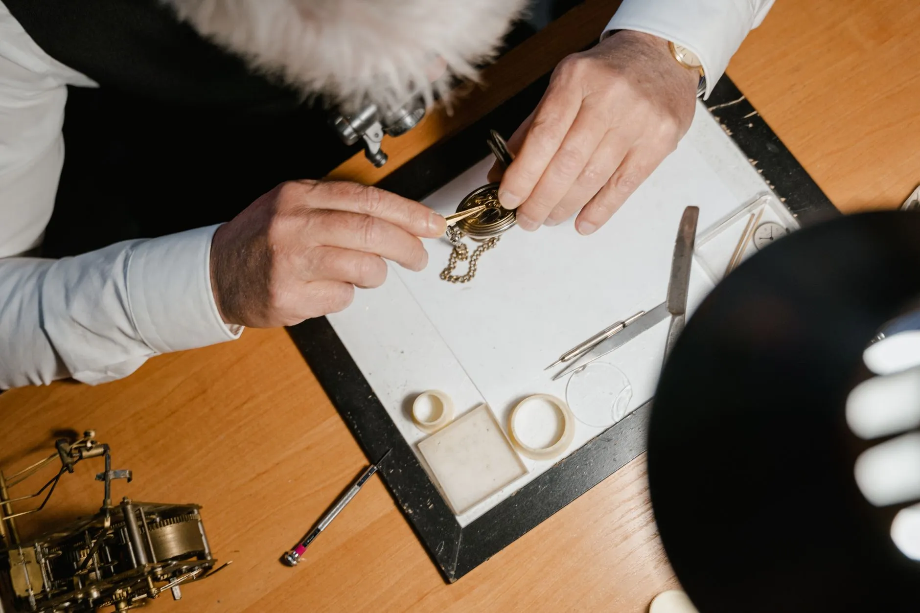 A watchmaker's hands over the bench, working on a watch