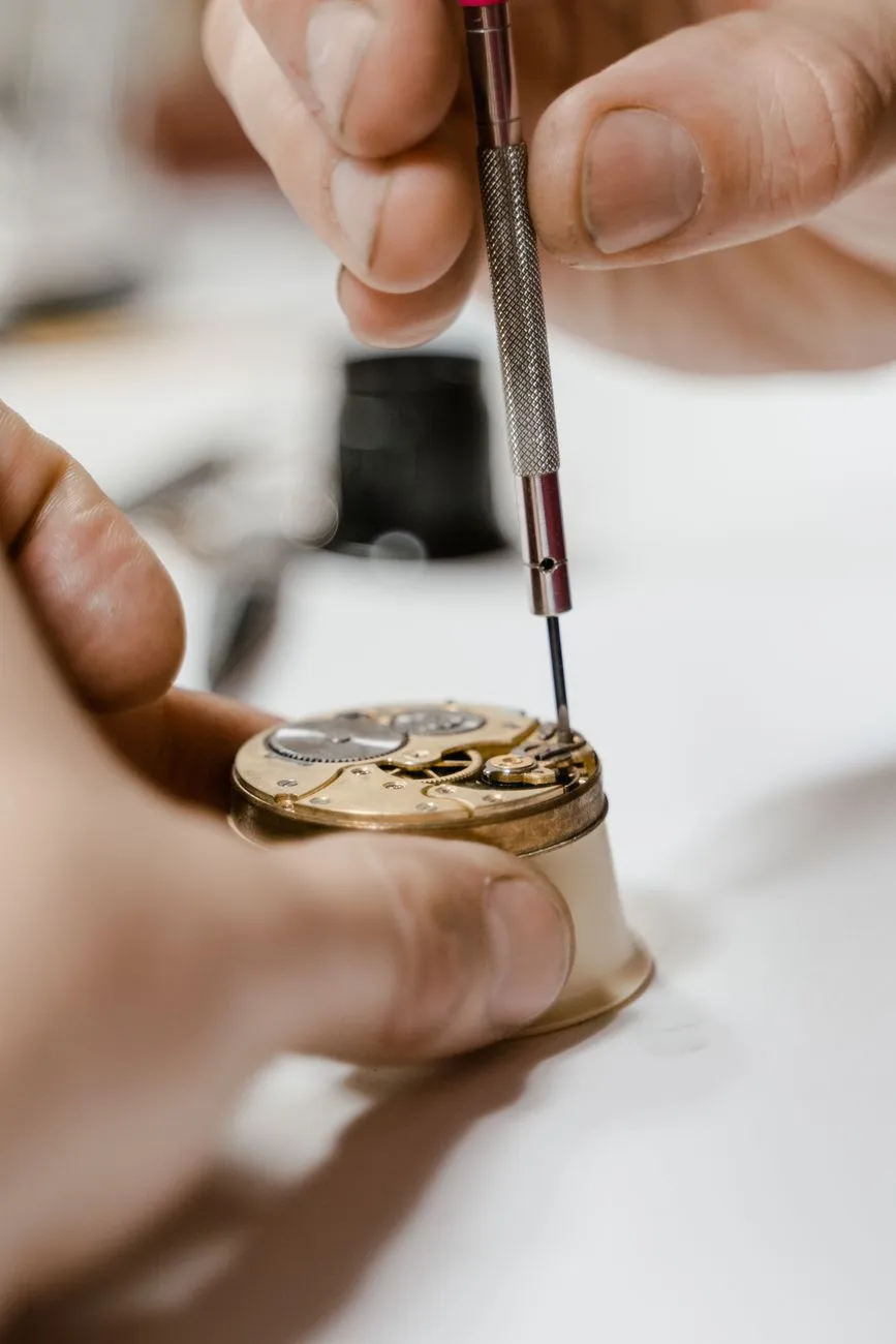 A movement in a holder being worked on with a fine screwdriver