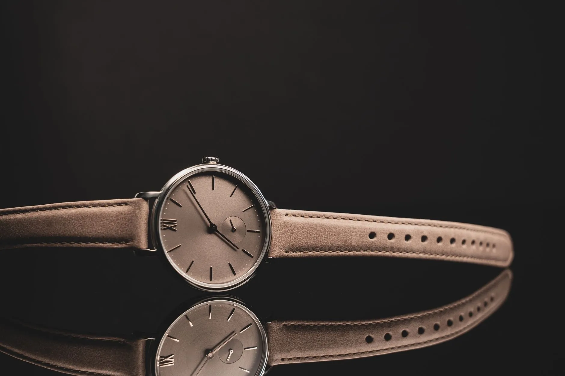 Osmund 38 Rosé with a brushed rosé dial and blush leather strap, reflected on a dark surface
